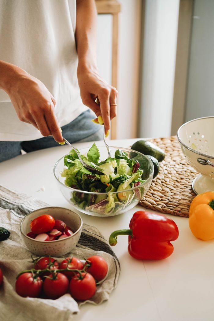 Mastering the First Impression: Your intriguing post title goes here A person mixes a fresh vegetable salad with tomatoes and bell peppers in a kitchen.